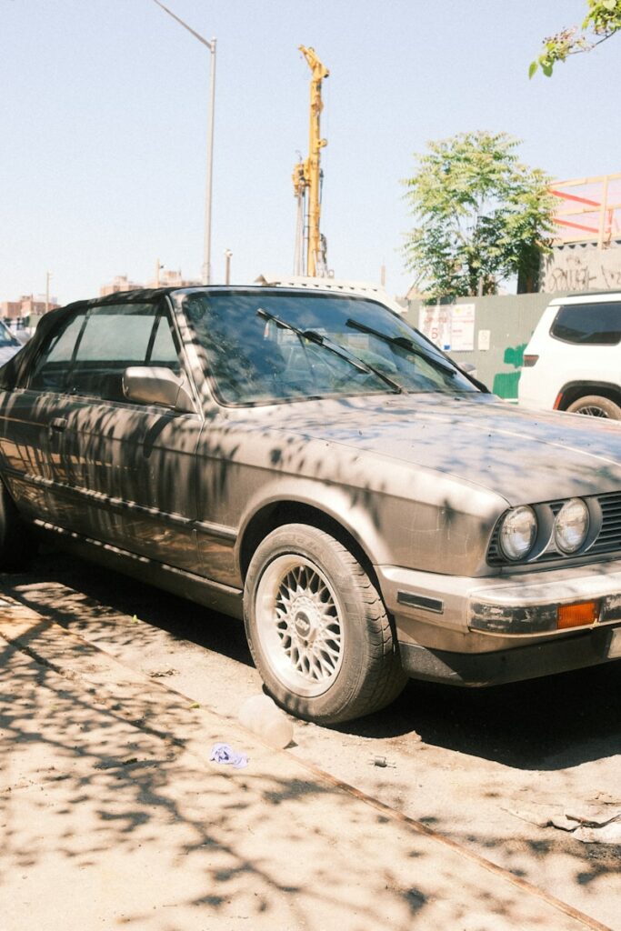 An old, dusty convertible car parked on the street.